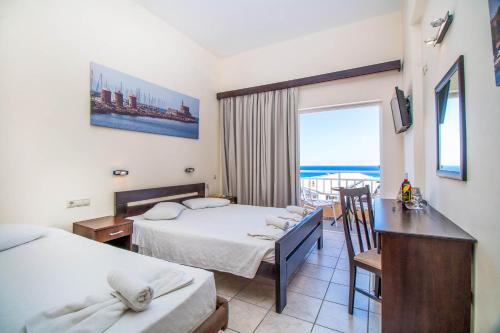 a hotel room with two beds and a desk and a balcony at Filmar Hotel, Ixia, Rhodes in Ixia