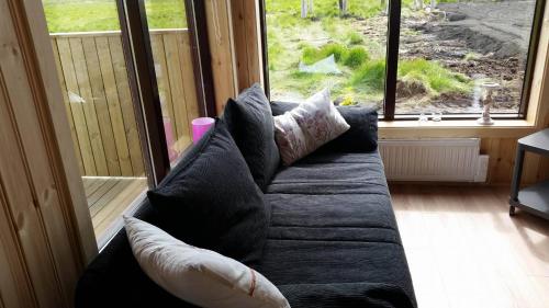 a couch with pillows sitting in front of a window at Hekla Cabin 2 Volcano and Glacier View in Hella