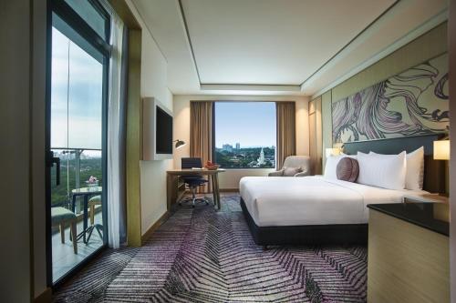 a hotel room with a bed and a desk and a window at Amari Johor Bahru in Johor Bahru