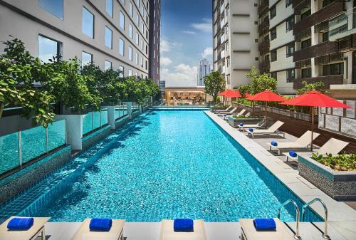 a swimming pool with chairs and umbrellas on a building at Amari Johor Bahru in Johor Bahru