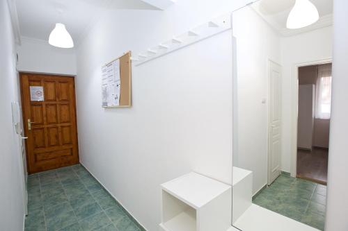 Habitación con pared blanca con banco y puerta en Zoli Apartmanok-Timi Kölcsey 34-36, en Hajdúszoboszló