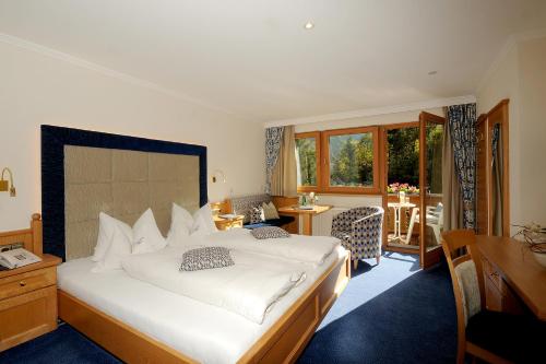 a bedroom with a large white bed and a desk at Hotel Garni Erler in Mayrhofen