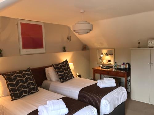 a hotel room with two beds and a desk at The Black Swan Inn in Norwich