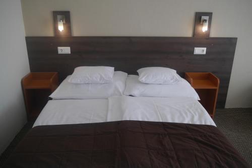 Hotel Tagore في بالاتونفوريد: سرير مع وسادتين بيضاء وجلستين ليلية