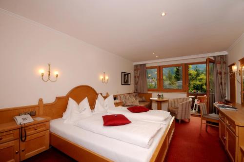 a bedroom with a large white bed with red pillows at Hotel Garni Erler in Mayrhofen