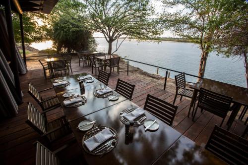Una mesa y sillas en una terraza junto al agua. en Zambezi Mubala Lodge, en Katima Mulilo