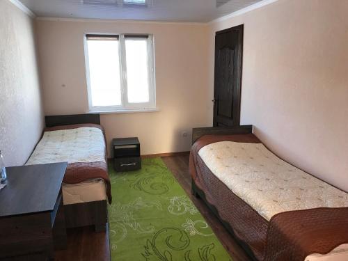 a room with two beds and a table and a window at Alakol-Jyrgalan Guest House in Dzhergalan