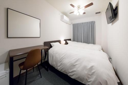 - une chambre avec un lit et un bureau avec une chaise dans l'établissement Rota Hostel, à Osaka