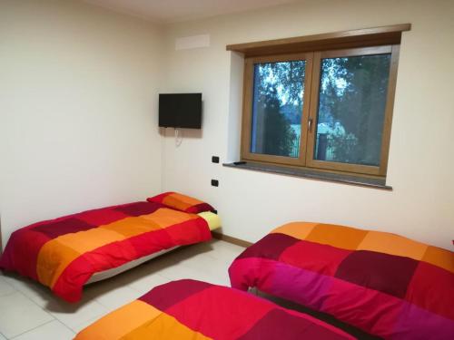 2 camas en una habitación con ventana en Appartamento vacanza "Le betulle", en Besnate