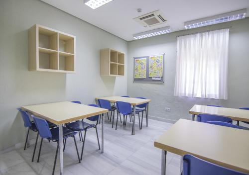 a classroom with tables and chairs and a window at Albergue Inturjoven Huelva in Huelva