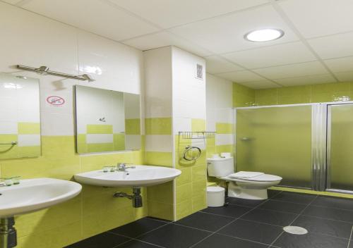 a bathroom with two sinks and a toilet and a shower at Albergue Inturjoven Huelva in Huelva