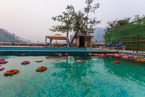 a large swimming pool with flowers in the water at Veda5 Ayurveda & Yoga Retreat in Rishīkesh