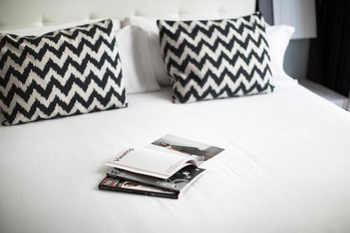 a bed with black and white pillows and a pile of magazines at Petit Palace Triball in Madrid