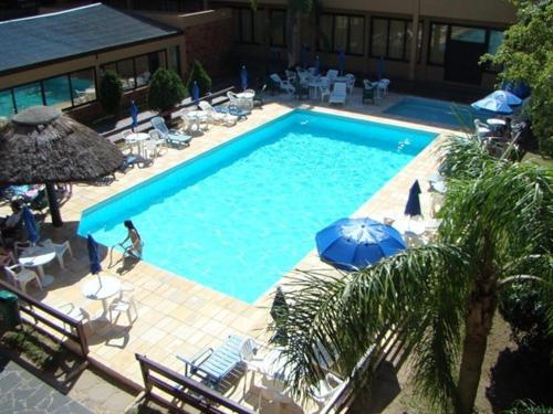 a large swimming pool with chairs and umbrellas at Hotel Fazenda Figueiras in Imbé