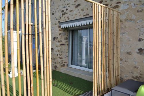 a building with bamboo fence next to a window at Chambre en Havre de paix in Panazol