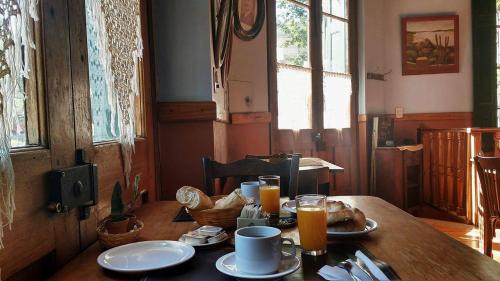 a wooden table with plates of food and orange juice at Hostería Restaurante del Puerto in Colón
