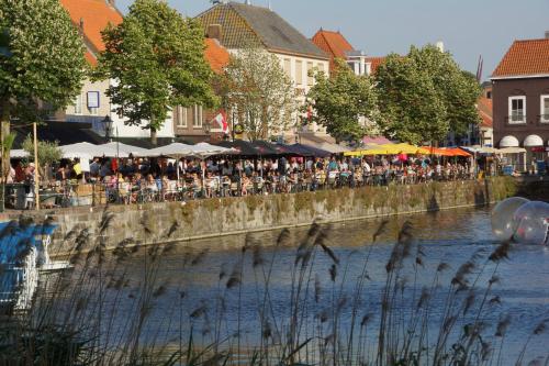 a group of people sitting on a wall next to a river at Rivers Hotel in Sluis