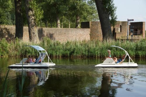 two children are riding in pedal boats on the water at Rivers Hotel in Sluis
