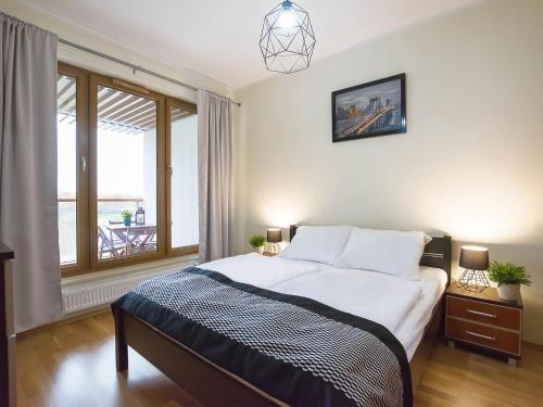 ein Schlafzimmer mit einem großen Bett und einem großen Fenster in der Unterkunft VacationClub - Olympic Park Apartment B307 in Kołobrzeg