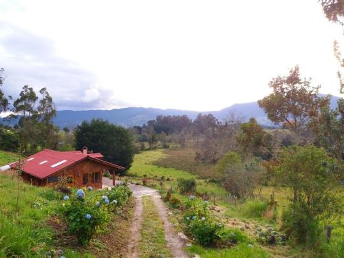 uma pequena casa num campo com uma estrada de terra em CASA LA KOCHA, Cabin, Hostal en la Laguna de la Cocha em El Encano