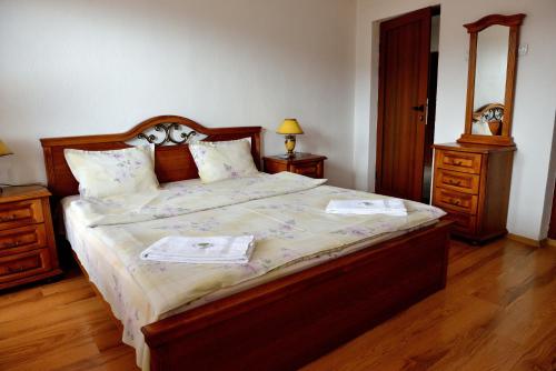 a bedroom with a large bed with a wooden headboard at Guest House Mavrudieva in Koprivshtitsa