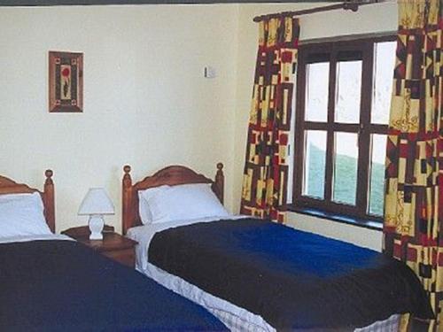 1 dormitorio con 2 camas y ventana en Kinsale Coastal Cottages, en Garrylucas