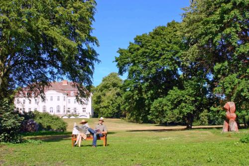 two people sitting on a bench in a park at Schloss Zinzow in Zinzow