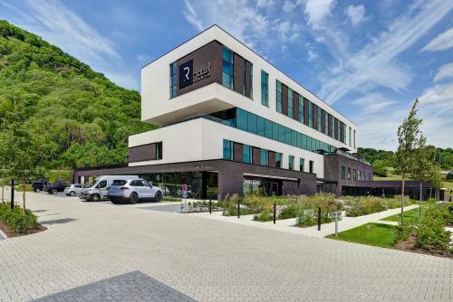 un gran edificio con coches estacionados en un estacionamiento en R hotel experiences, en Sougné-Remouchamps