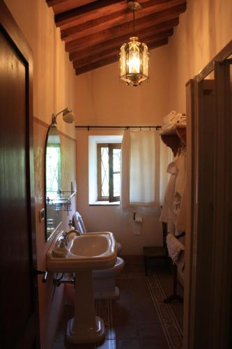 a bathroom with a sink and a toilet and a chandelier at Il Fico in Chianti in Gaiole in Chianti
