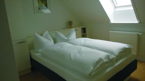 a white bed with white pillows and a window at Hof Hanau in Dörgenhausen