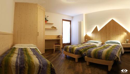 a bedroom with two beds and a desk in it at Appartamenti Bazzanella in Andalo