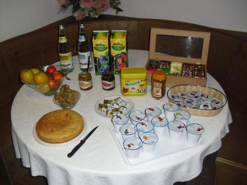 een witte tafel met eten en drinken erop bij Agriturismo Cornolade in Ponte nellʼAlpi
