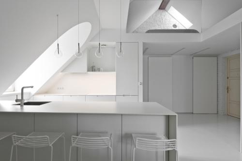 a kitchen with white cabinets and a sink and stools at City Entrance Apartment in Vilnius