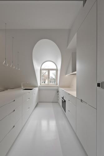 a white kitchen with white cabinets and a window at City Entrance Apartment in Vilnius