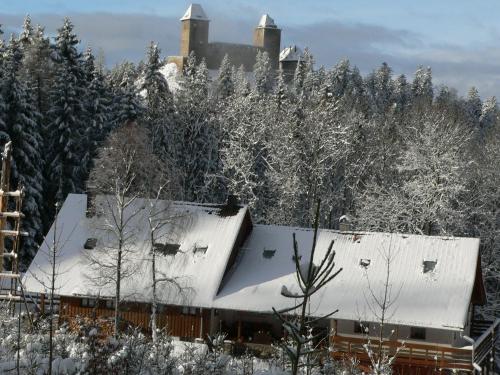 a house covered in snow with trees in the background at Penzion Na Habeši in Kašperské Hory