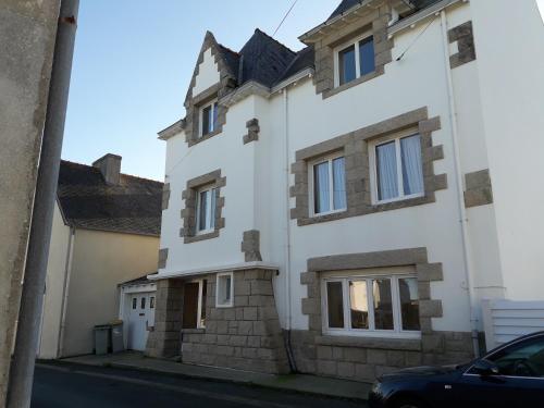 une maison blanche avec une voiture garée devant elle dans l'établissement appartement proche de la mer, au Guilvinec