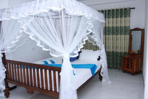a bedroom with a canopy bed with white curtains at Resort of Happiness in Mirissa