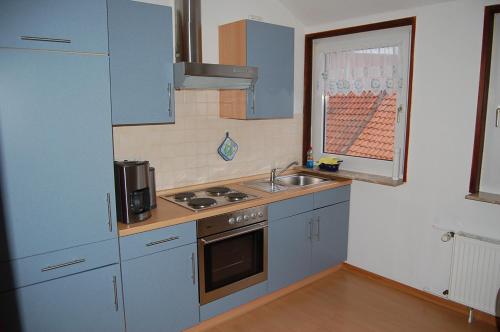 Elle comprend une petite cuisine avec des placards bleus et un évier. dans l'établissement Ferienwohnung Stollenwerk am Steinhuder Meer - Wunstorf OT Steinhude An der Schanze 7, à Steinhude