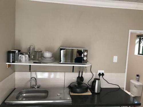 a kitchen with a sink and a microwave on a shelf at B@home in Bloemfontein