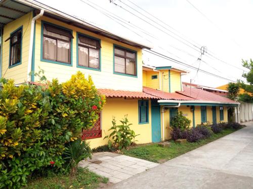 a yellow and blue house next to a street at Casa Marbella in Tortuguero