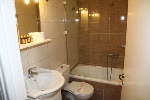 a bathroom with a sink and a toilet and a shower at Hotel Panellinion in Tríkala