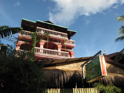 ein hohes rotes Gebäude mit Balkon oben in der Unterkunft Bun Kao Guesthouse in Siem Reap