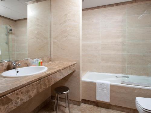 a bathroom with a sink and a tub and a toilet at Apartamentos TH La Florida in Madrid