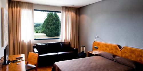 Pokój hotelowy z łóżkiem, krzesłem i oknem w obiekcie AS Hoteles Altube w mieście Zuia