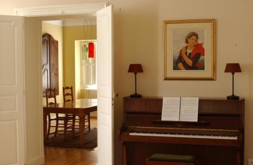 a piano in a living room with a painting on the wall at Clos Mirabel Manor - B&B in Jurançon