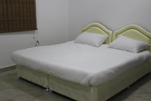 a bed with white sheets and pillows in a room at Beyout Guest Houses in Ma‘mad