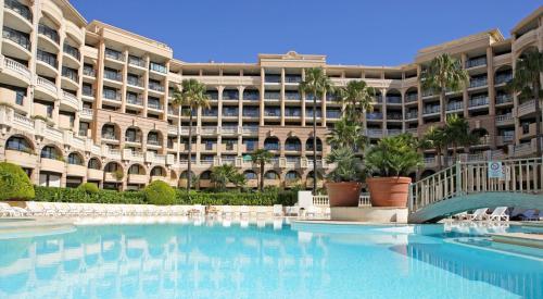 - un grand bâtiment avec une grande piscine en face dans l'établissement Cannes vue mer, à Cannes