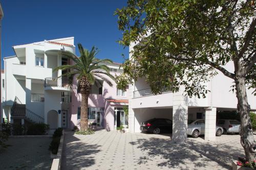 a white building with a palm tree in front of it at Apartmani Pašalić in Tučepi