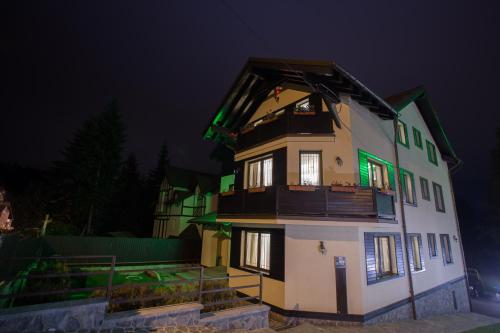 a large house with green lights on it at night at Pensiunea Carmen`s Mansion B in Sinaia