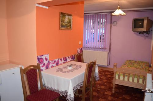 una sala da pranzo con tavolo, sedie e TV di Apartmani Bojović a Zlatibor